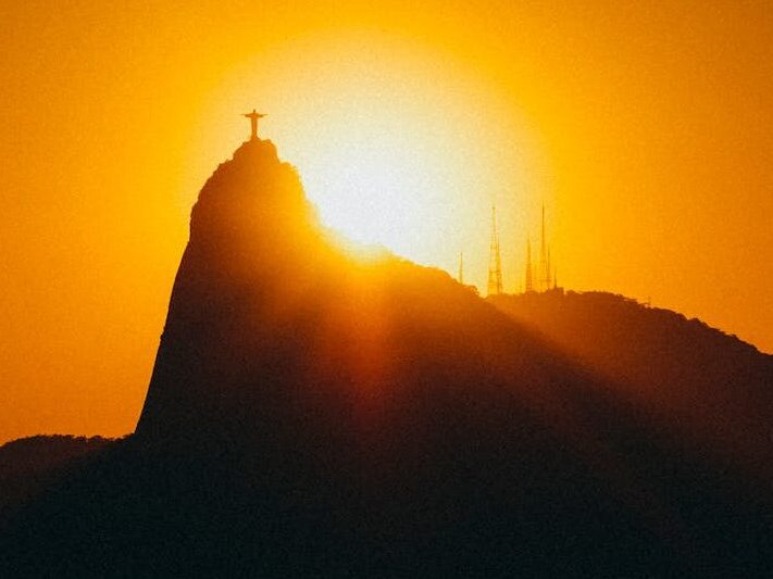 Silhouette of Sugarloaf Mountain at sunset with boats and calm sea in Rio de Janeiro, Brazil.